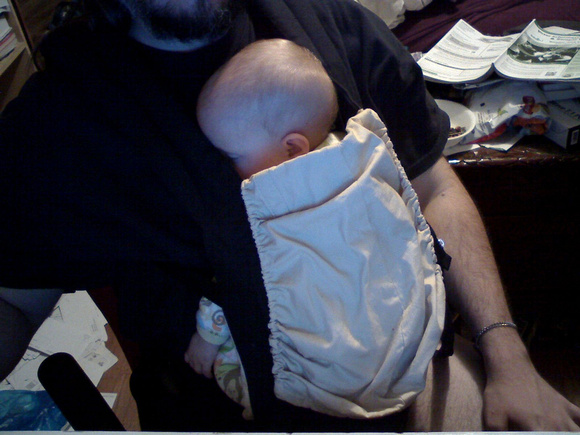 Turns out that if the baby is already asleep, but is waking up when not lying on a person (as they are consistently this week), we can put the baby carrier on *over* the baby and she'll stay asleep.