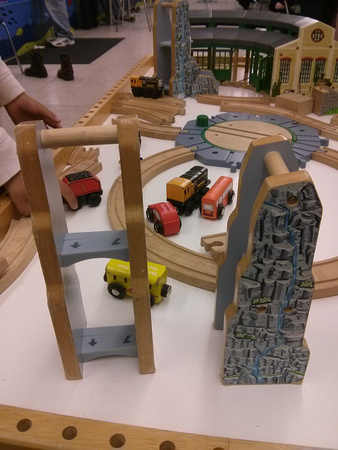 So the things in the foreground are parts of the wooden train set in the background; they're the same piece from two different angles.  What are they *for*?