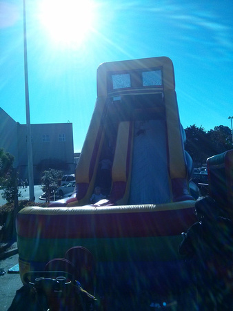 Babies playing on a very tall bouncy house slide.