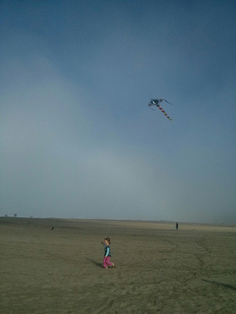 K flying a kite at the beach.